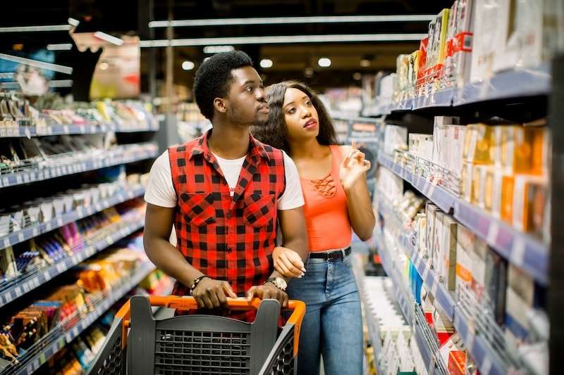 Shows a couple in a grocery store chooseing products from the shelf. 